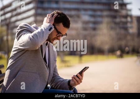 Young businessman is using smartphone in park. Stock Photo