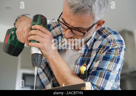 Mature man using power drill at home Stock Photo