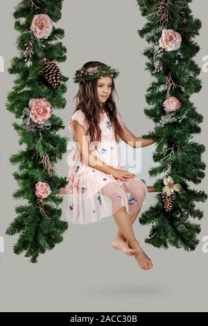 Happy child girl on swing with Christmas decorations in studio Stock Photo