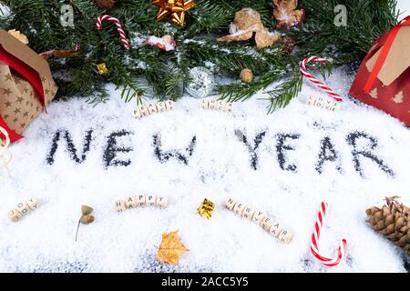 'New Year' written in snow together with christmas ornaments, peace, luck, love, happy, joy - New Year concept Stock Photo