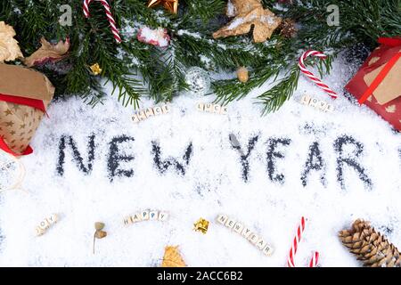 'New Year' written in snow together with christmas ornaments, peace, luck, love, happy, joy - New Year concept Stock Photo