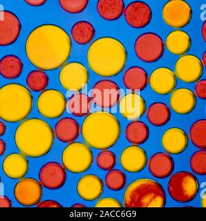Variation in the molecular properties of different liquids, illustrated by a background of blue two stroke oil and a mixture of red and yellow droplet Stock Photo
