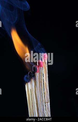 Lit match. Matches being lit in a sequence, one after the other. A match head ignites when provided with heat through friction. Match heads are often Stock Photo