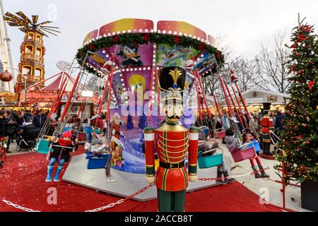 PARIS, FRANCE - NOVEMBER 30, 2019: kids having fun on a swing ride carousel in the Christmas Market at The Tuileries Garden in Paris. A giant wooden p Stock Photo