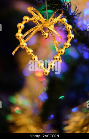 Heart shaped Christmas ornament hanging on a nicely decorated Christmas tree Stock Photo