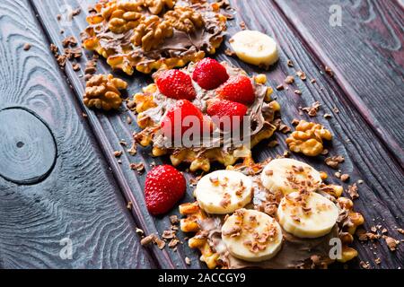 waffles with chocolate paste, strawberry, banana and nuts Stock Photo