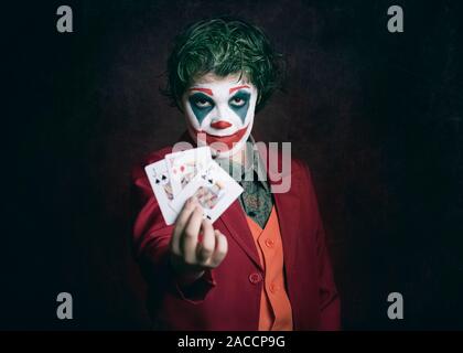 boy dressed as Joker with poker cards on dark background Stock Photo