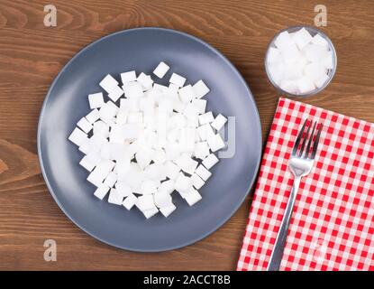 Sugar cubes on a plate and in a glass. Too much sugar in food concept Stock Photo