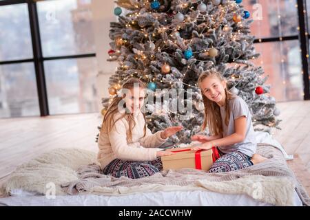 Happy kids having fun and opening presents near Christmas tree.