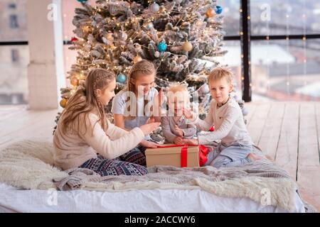 Happy kids having fun and opening presents near Christmas tree.