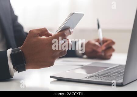African american businessman using smartphone and taking notes in office Stock Photo