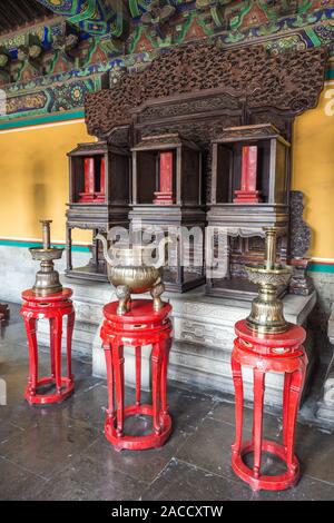 Ancient Chinese bronze dishes on the red stands in the room. Stock Photo