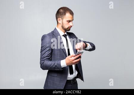 On the way to success. Young attractive businessman, talking on a smartphone, smiles and looks at his watch on a white background Stock Photo