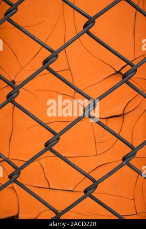 Orange background of old peeling paint and mesh netting. Stock Photo