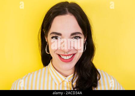 Portrait of a young beautiful brunette woman posing on a yellow background Stock Photo