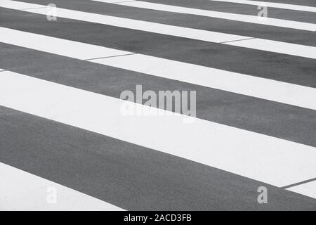 close-up zebra crossing or crosswalk background - abstract pattern with white stripes on gray asphalt Stock Photo