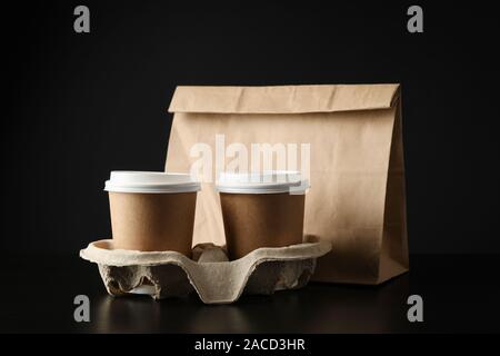 Eco - friendly package and coffee cups on black background, space for text Stock Photo