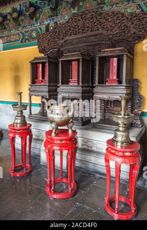 Ancient Chinese bronze dishes on the red stands in the room. Stock Photo