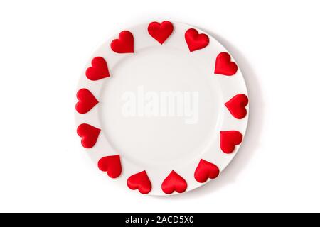 White plate surrounded by hearts on white background Stock Photo