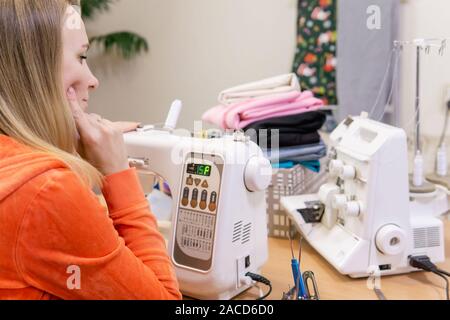 seamstress woman reflects on settings for home sewing machine Stock Photo