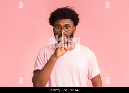 Handsome silent black man with glasses making hush gesture Stock Photo