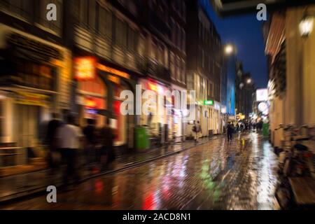 Blurry motion image of people walking on Warmoesstraat street in Amsterdam. It is one of the main shopping streets with cafes, restaurants and shops. Stock Photo