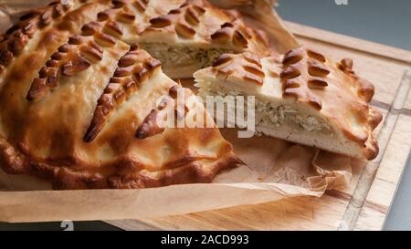 Close-up homemade cabbage pie on a cutting board. Russian and Ukrainian traditional national cuisine. Food Delivery Concept Stock Photo