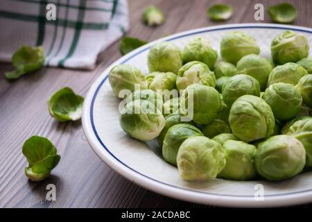 organic raw and fresh brussel sprouts on a plate with a wooden background Stock Photo