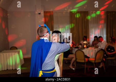 A groom dressed as Batman having fun with his new wife during their first dance, traditional wedding celebration, fun, funny dance, humour Stock Photo