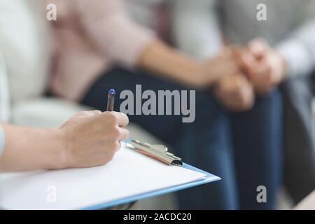 Therapist writing in blank notepad at family counseling session Stock Photo
