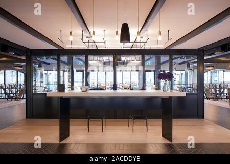 Informal meeting areas with communal tables. Devon House, London, United Kingdom. Architect: Stiff + Trevillion Architects, 2019. Stock Photo