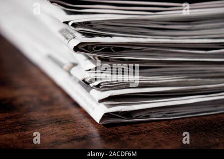 pile of newspapers or papers on wooden table - print media news Stock Photo