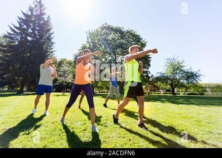 group of friends or sportsmen exercising at park Stock Photo