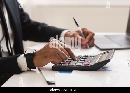 Close up of man checking on incomes, using calculator Stock Photo