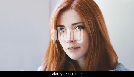 young woman with red hair and freckles - redhead girl with freckly or freckled face - indoor portrait with natural light Stock Photo