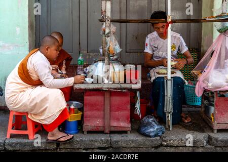 Two Young Thilashin (Young Buddhist Nuns) Eating Lunch At A Street Food Stall In Downtown Yangon, Yangon, Myanmar. Stock Photo