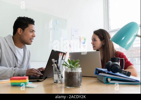 Coworkers using laptops in office Stock Photo