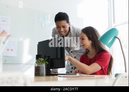 Coworkers smiling at computer together Stock Photo