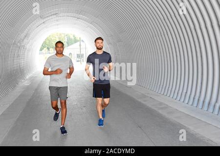 young men or male friends running outdoors Stock Photo