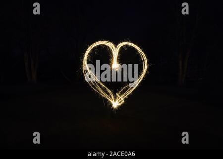 heart shape light painting with sparklers outdoors at night - symbol for love and romance Stock Photo