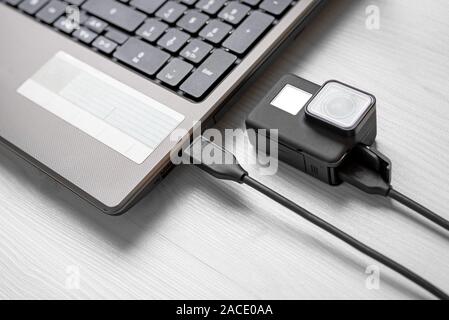 Action camera connected to laptop via usb cable. Close-up. Stock Photo