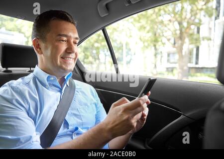 passenger or businessman using smartphone in car Stock Photo