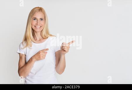 Look here! Happy woman pointing aside on copy space Stock Photo