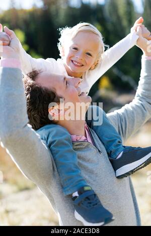 Son sitting on father's shoulders in nature Stock Photo