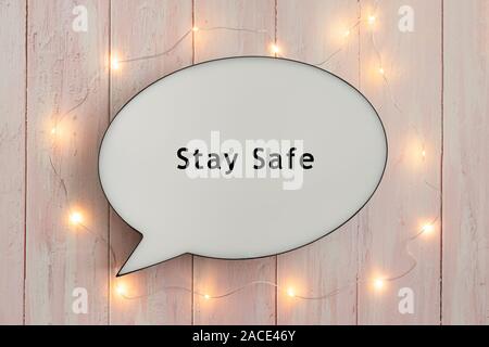 Stay Safe written on speech bubble, surrounded by bright lights on pink wooden background Stock Photo