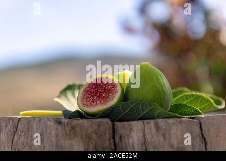 fresh figs on fig tree leaf, on wooden base blurred background Stock Photo