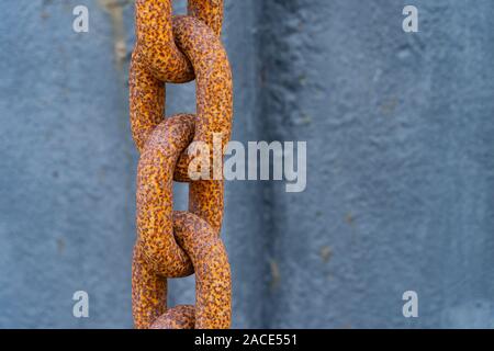 A thick rusty orange chain in front of blue background - security concept Stock Photo