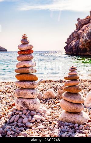 Two towers of flat stones on the beach. Rock balancing or stone stacking is the art discipline, or hobby in which rocks are naturally balanced on top Stock Photo