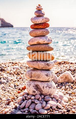 The tower of flat stones on the beach. Rock balancing or stone stacking is the art discipline, or hobby in which rocks are naturally balanced on top o Stock Photo