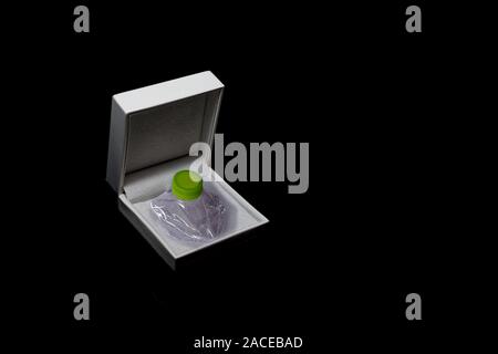 Crushed plastic bottle stored in a jewelry box on a black background Stock Photo